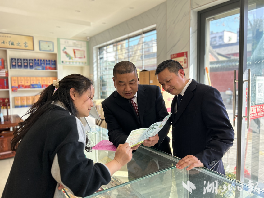 图为专卖执法人员走访市场上宣传“码上纠风”使用手册