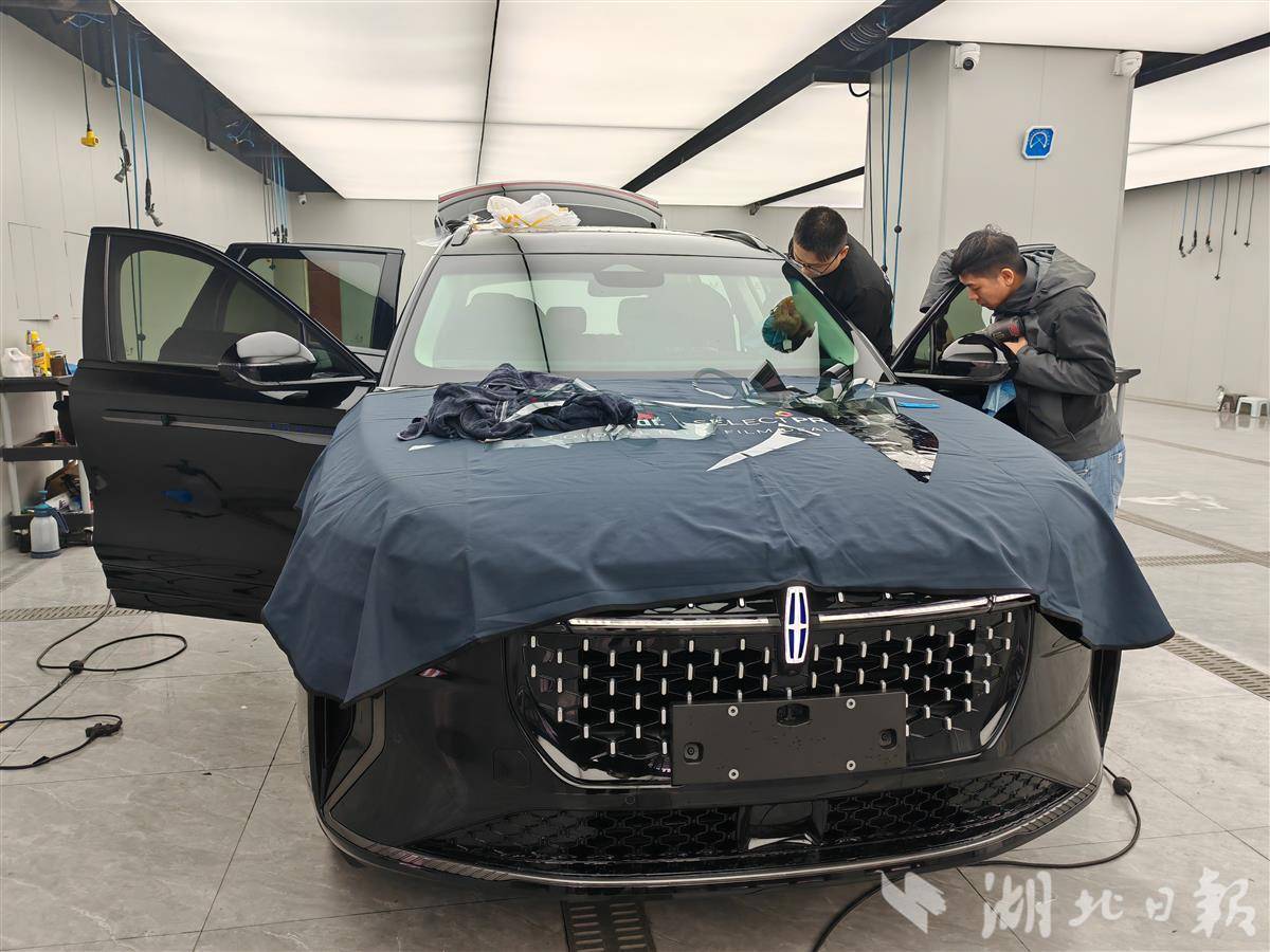 位于洪山区的龙膜全球臻选店，师傅正在贴车窗膜。（左晨摄）