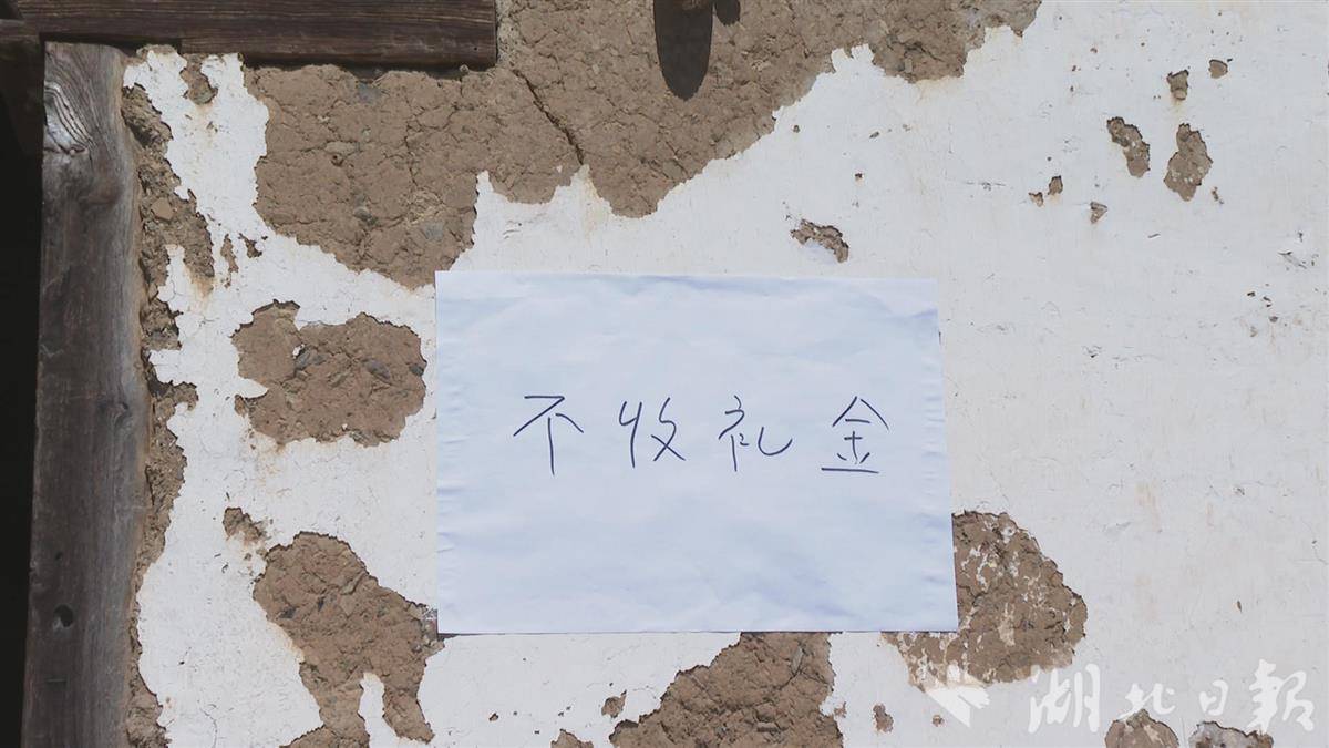 斑驳的土屋墙面，仍然张贴着写有“不收礼金”的白纸。