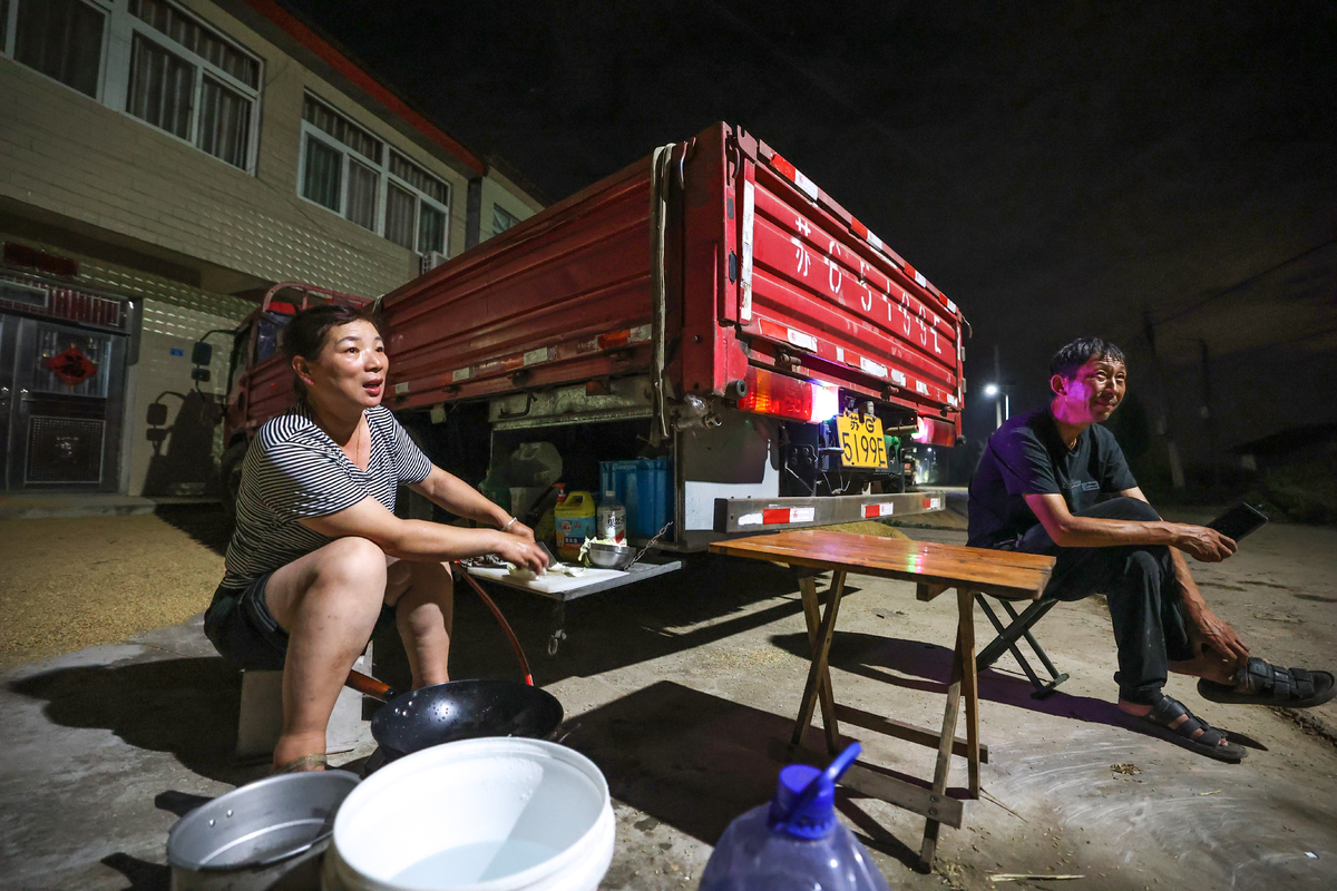 9月15日晚，南漳县武安镇安乐堰村路边，来自陕西、安徽、江苏等地的农机手们收工后开始生火做饭。（黄俊 摄）