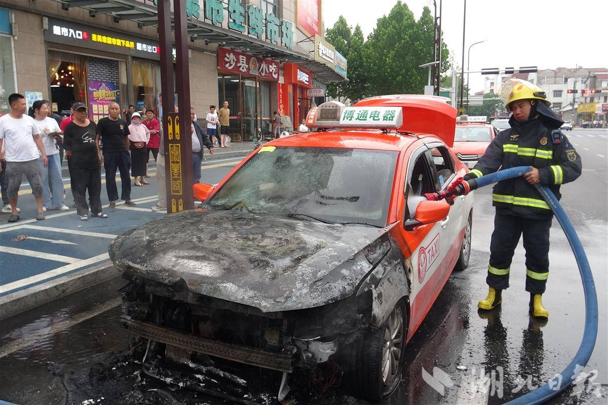 消防救援人员对自燃的出租车进行灭火。李逸/摄