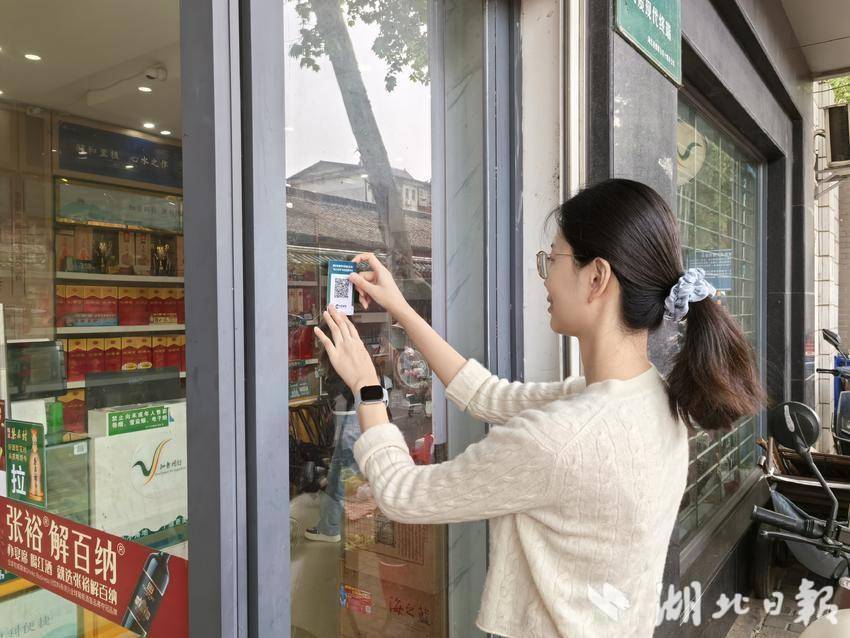 图为客户经理为零售户张贴“码上纠风”二维码
