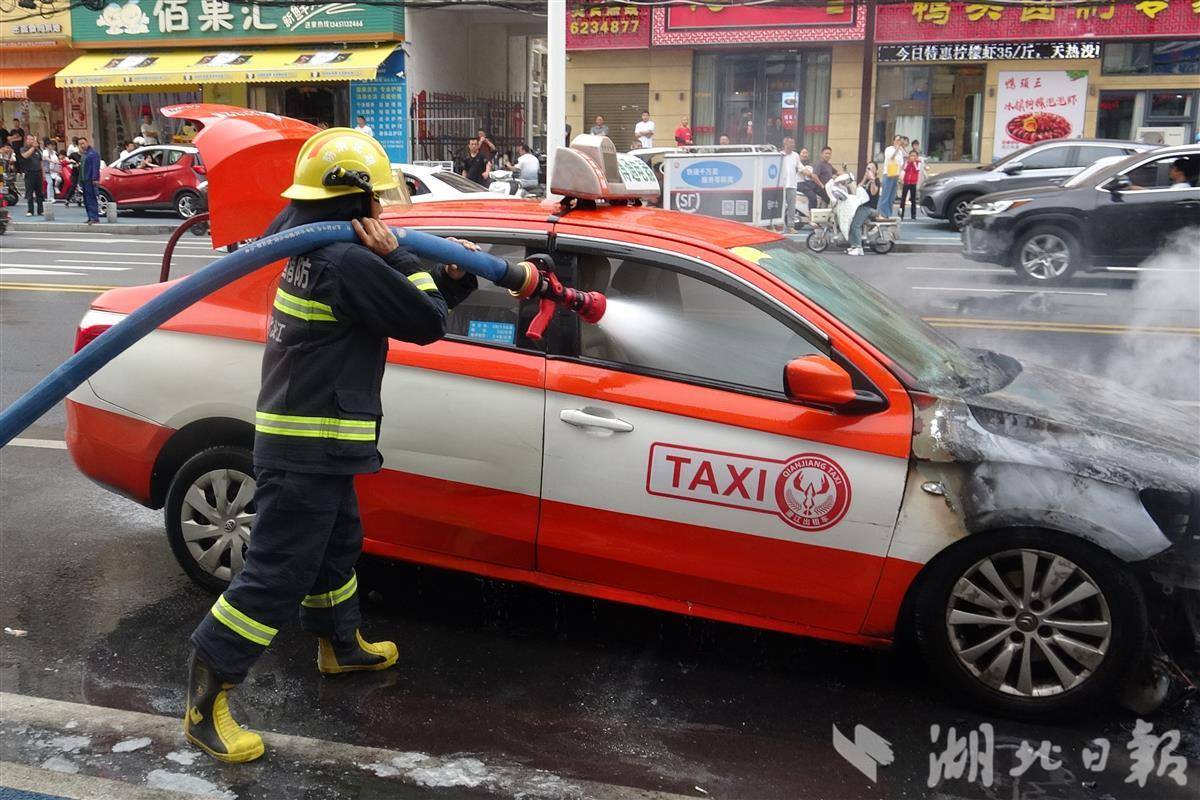 消防救援人员对自燃的出租车进行灭火。李逸/摄