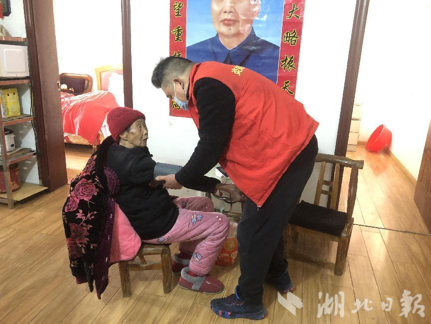 工作人员为老人测量血压，叮嘱老人注意饮食和睡眠