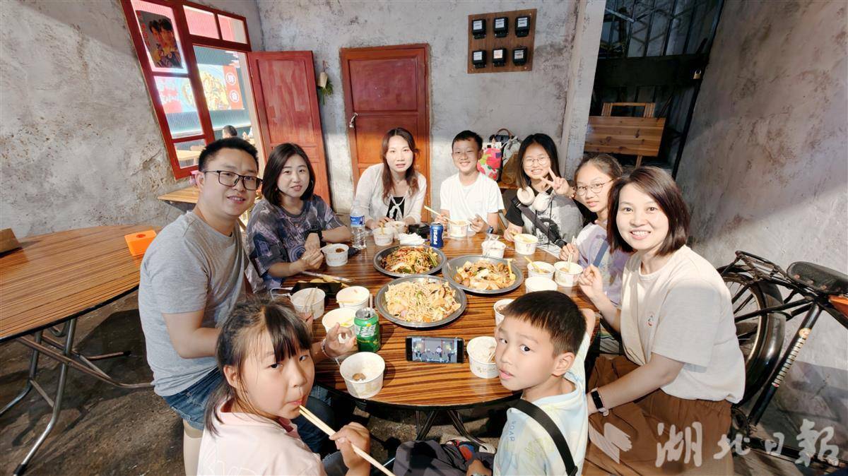 何建堂与亲朋好友在楚风汉味美食街区品尝美食。（湖北日报全媒记者 张灿摄）