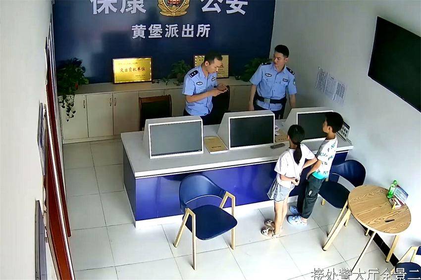 两名学生将拾到的手机交给民警（视频截图）