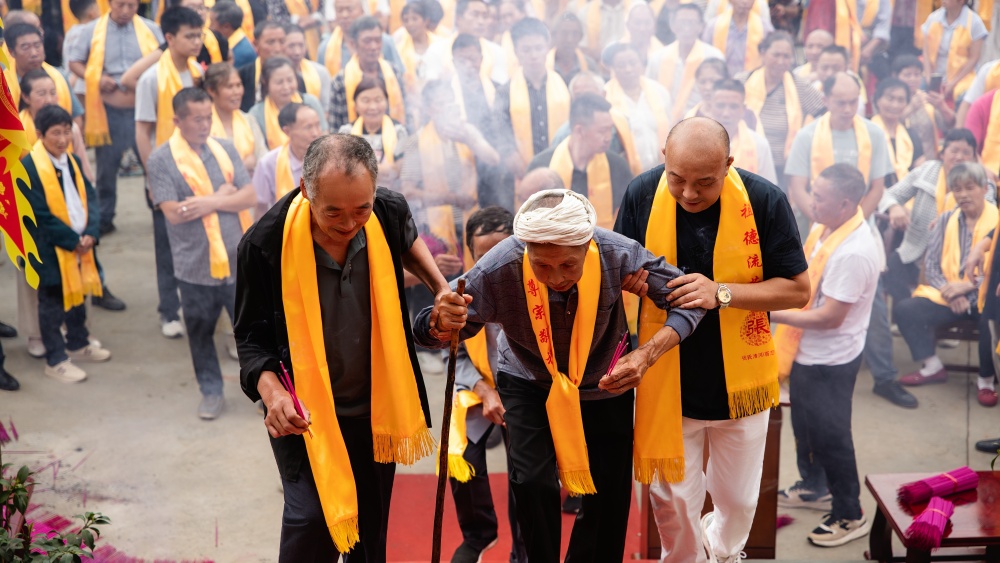 图一：年过九旬的张凤松在晚辈搀扶下向祖宗牌位叩拜_副本