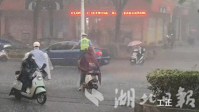 谷城县公安局交警大队民警冒雨执勤、疏导交通。