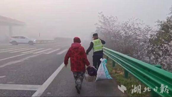 浓雾锁国道，巡逻交警安全护送挑担赶集的老大娘