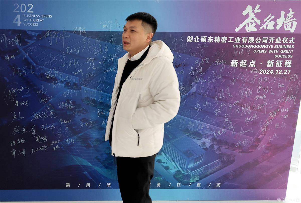 钟文星站在公司开业仪式签名墙前。湖北日报全媒记者 汪洋 摄