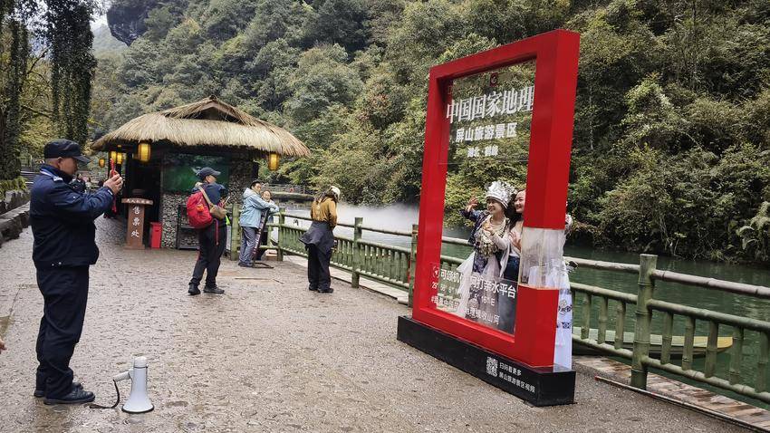 图为景区保安为游客拍照