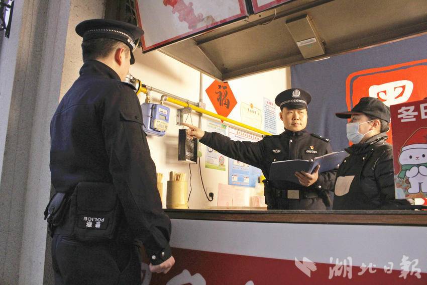 邓胜（中）提醒商户用火用电安全