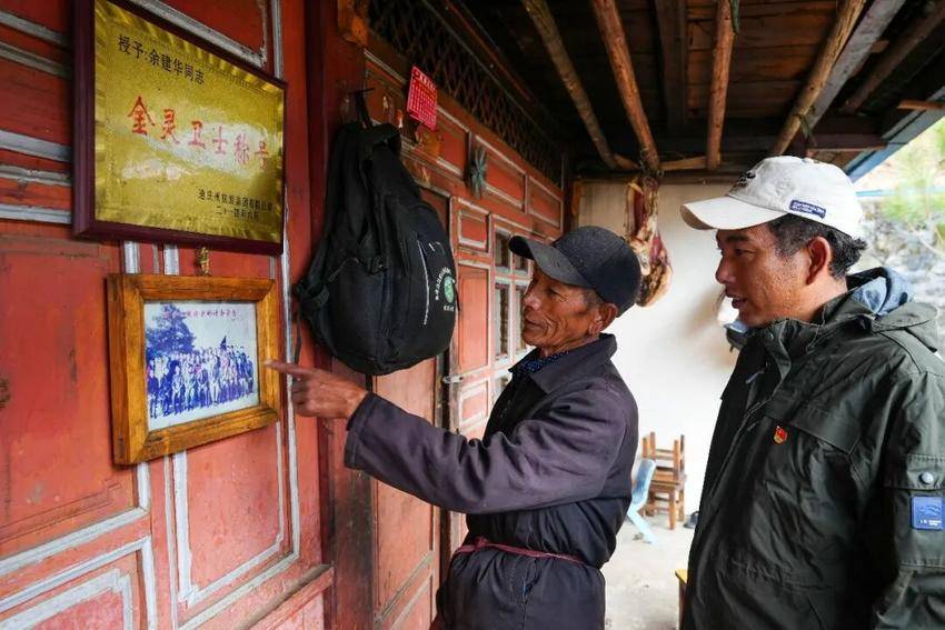 余建华(左)给儿子介绍2007年参加“滇金丝猴保护研讨会”时的情景。