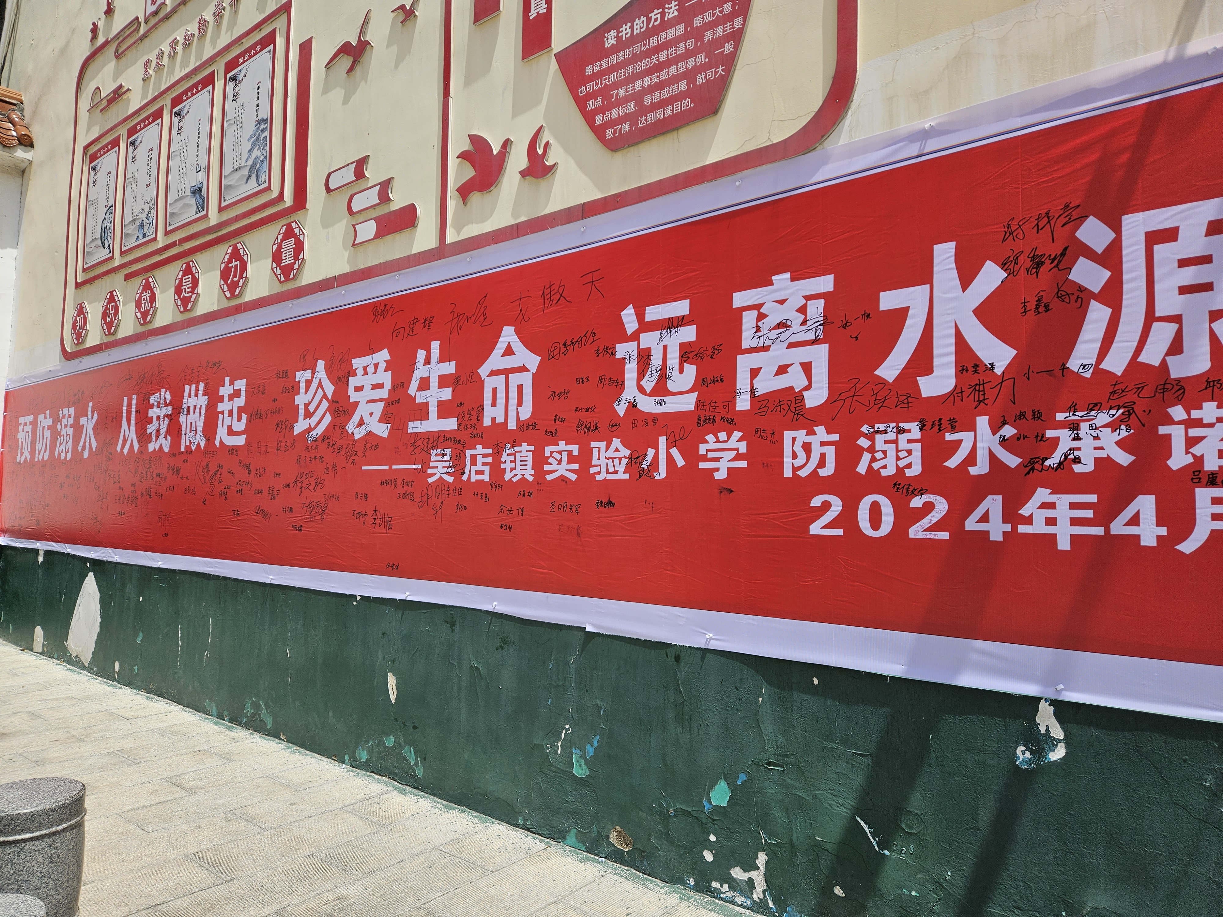 学生们在印有"预防溺水,从我做起,珍爱生命,远离水源"的红色条幅上