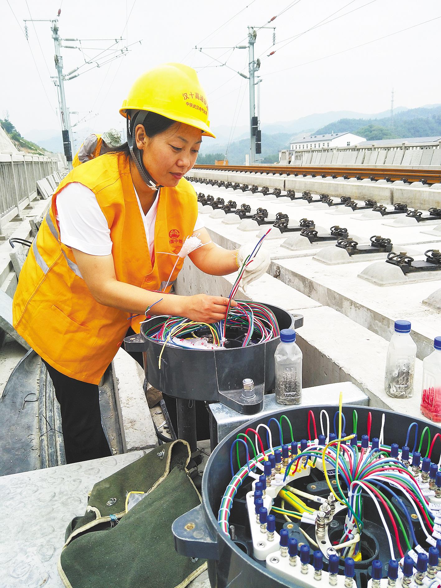王艳鸽冒着高温在铁路沿线为信号电缆箱盒配线.