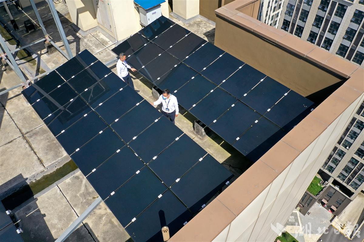 在武汉市东西湖区宏图里小区楼顶,物业工作人员正在查看太阳能电池板