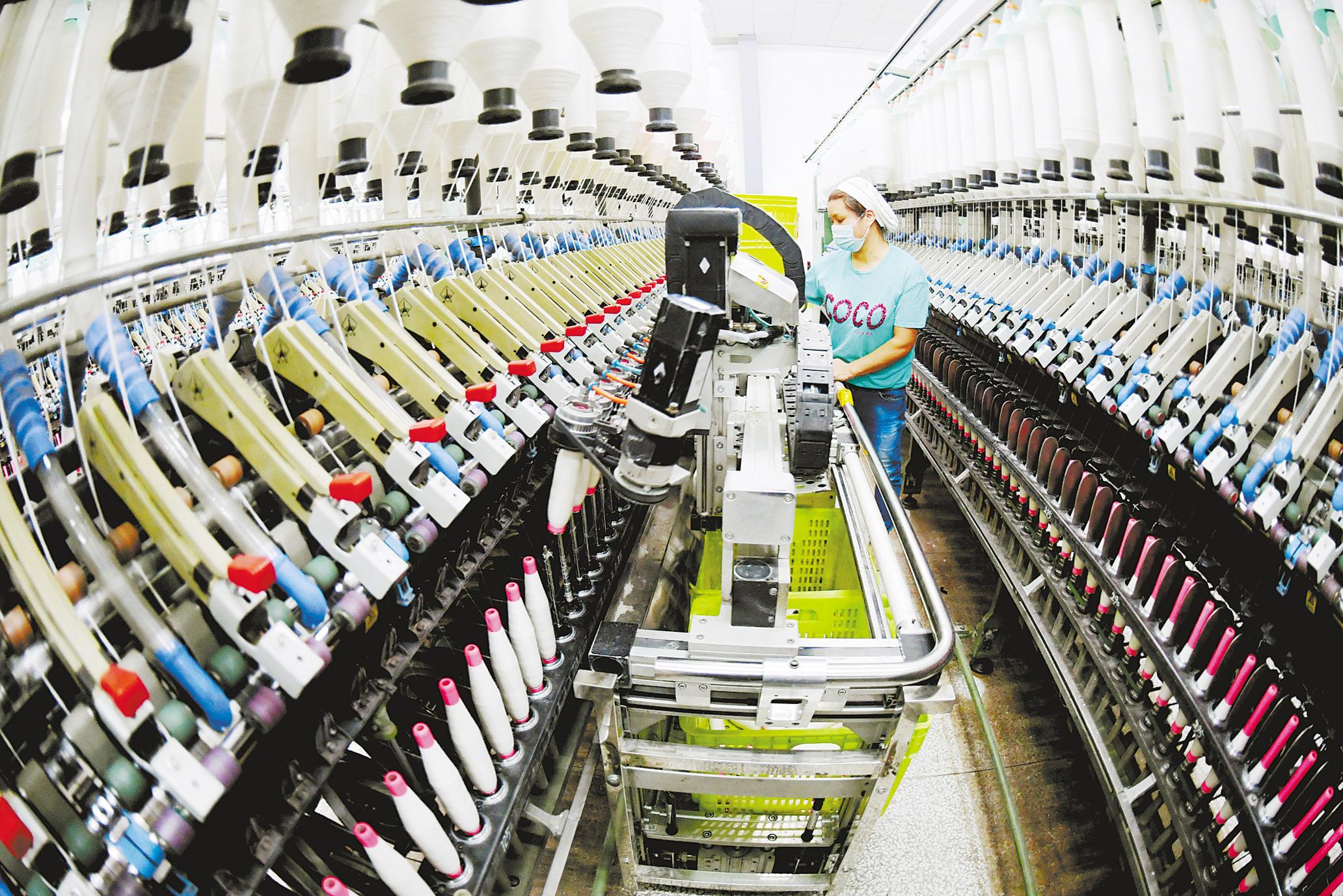 1月20日,在襄阳九天纺织有限公司车间,络筒机器人在生产线上高速运作.