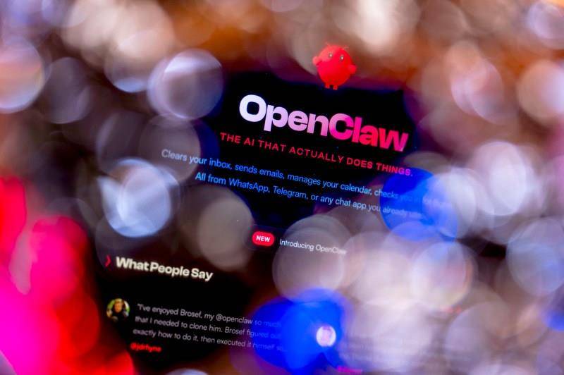 A computer screen displaying the OpenClaw website with the tagline 'THE AI THAT ACTUALLY DOES THINGS' in red text and 'Clears your inbox, sends emails, manages your calendar, checks you in for flights. All from WhatsApp, Telegram, or any chat app you already use' underneath in blue. 