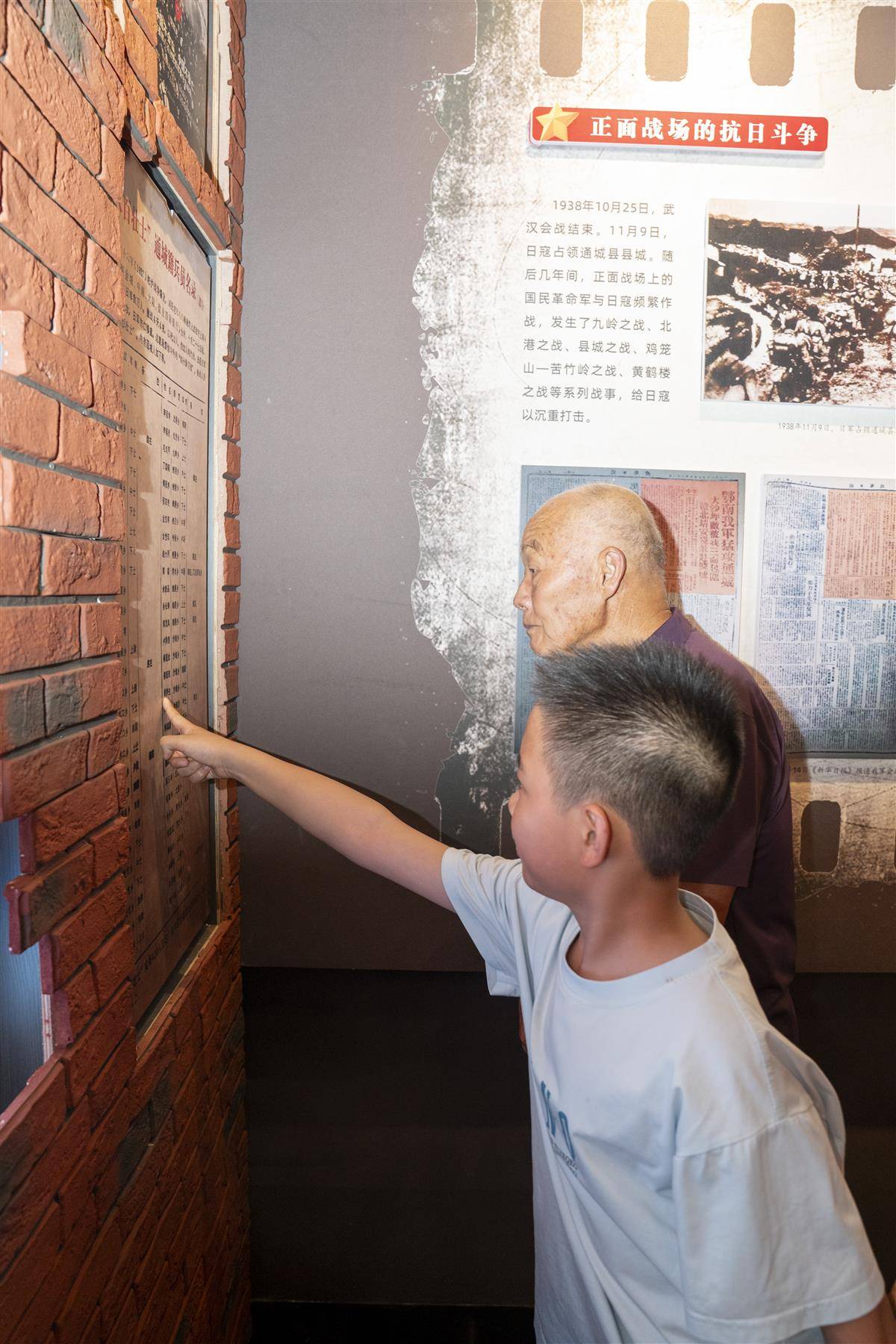 胡战平和孙子在八百壮士史料展板上寻找父亲胡梦生的名字.jpg