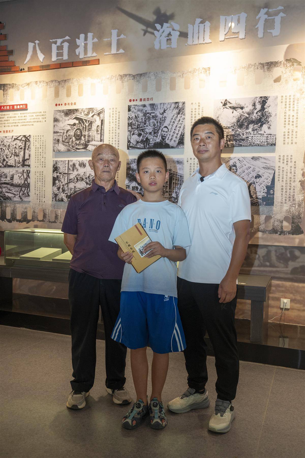 胡志全（右一）和父亲、儿子在通城县档案馆八百壮士史料展览前合影.jpg